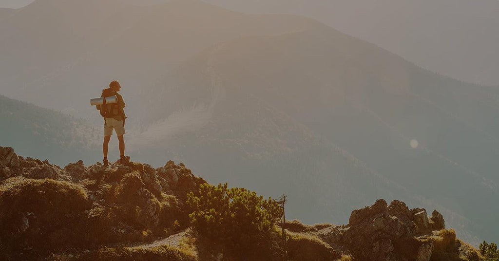 Man standing on mountaintop hiking trail overlooking valley